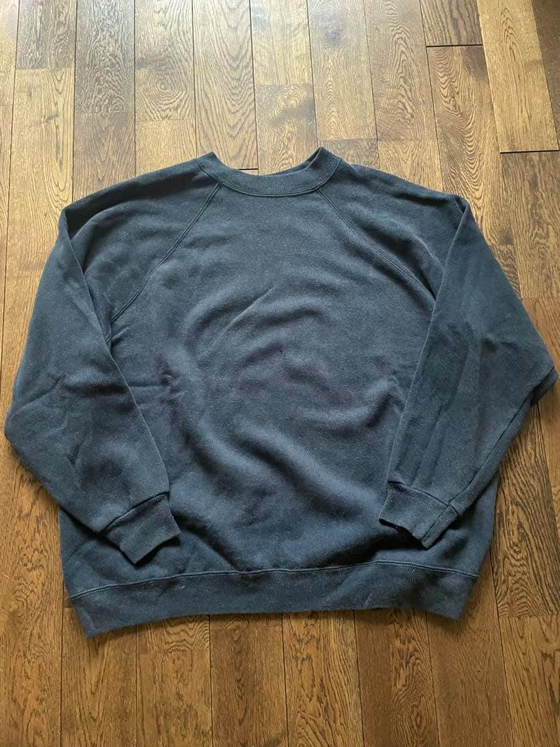 Black Hanes crewneck sweatshirt laid flat on a wooden floor.