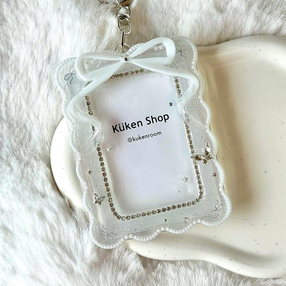 White glittery resin card-style keychain with a decorative bow and rhinestone-lined clear window showing a paper insert reading "Küken Shop".