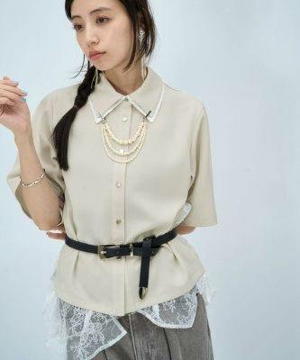 Model wearing a beige women's polyester short-sleeve shirt with button front and lace layered irregular hem.
