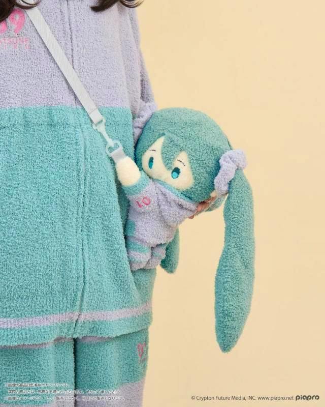 A person wears and holds a teal-green Hatsune Miku 2WAY fluffy plush bag clipped to a shoulder strap.