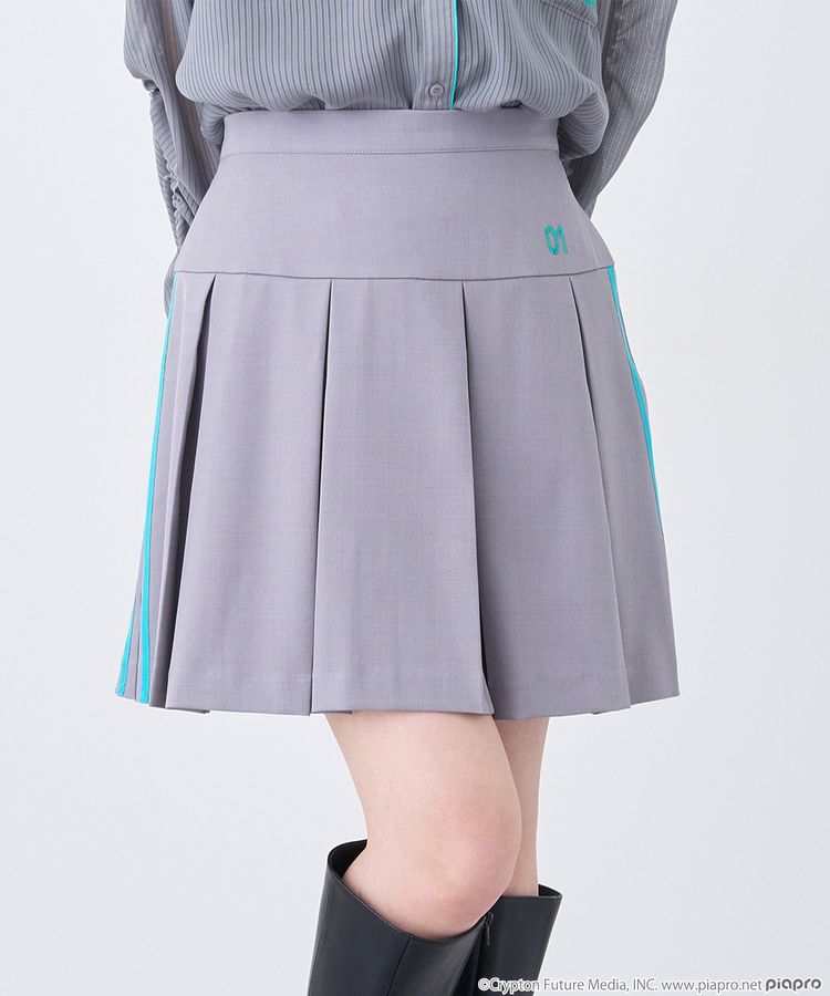 Front view of a gray pleated mini skirt with teal side stripes worn by a model.