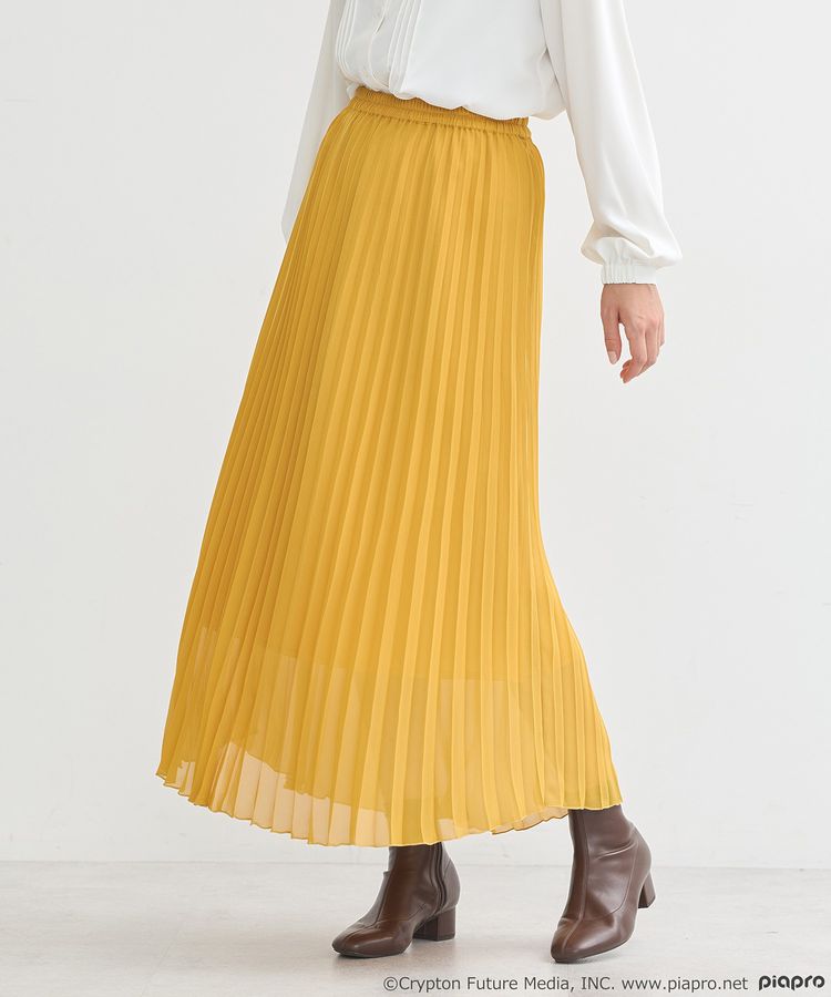 Model wearing a yellow chiffon pleated women's skirt (polyester) with a white blouse and brown ankle boots.
