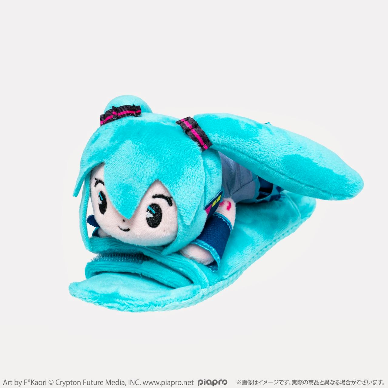Front-angle photo of the Hatsune Miku shoulder-pad plush showing the character's head, twin tails, and the turquoise shoulder pad.