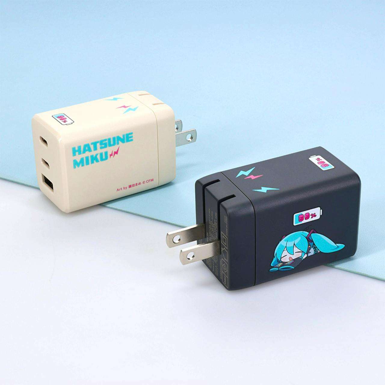 Two Hatsune Miku–themed USB wall chargers (cream and dark) shown with prongs and USB ports visible.