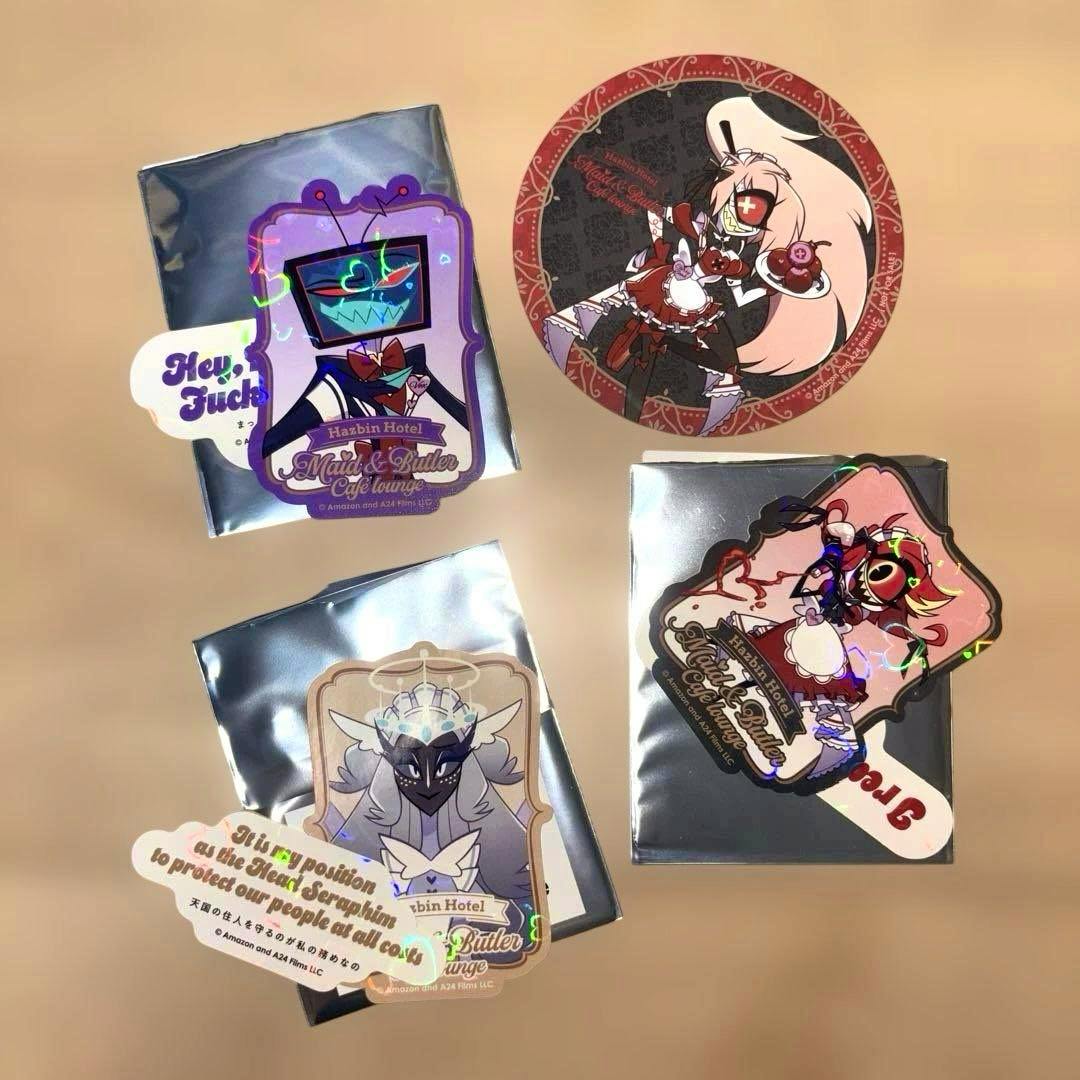 Several Hazbin Hotel character stickers and a round character coaster displayed on silver backing pouches on a beige surface.