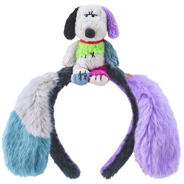 Front view of a colorful furry headband with long floppy ears and a small plush dog attached on top.