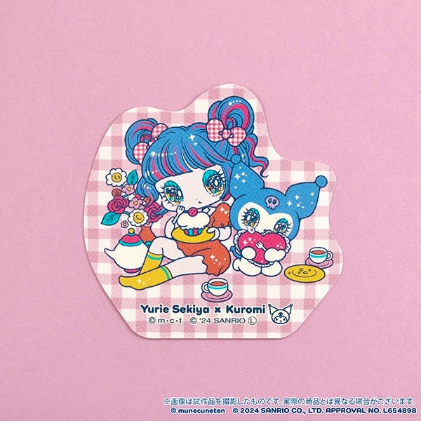 Close-up photo of a single Yurie Sekiya × Kuromi sticker showing a blue‑haired girl seated beside Kuromi with teacups and sweets on a pink gingham background.