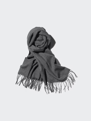 A dark gray acrylic scarf with fringed ends arranged on a light background.