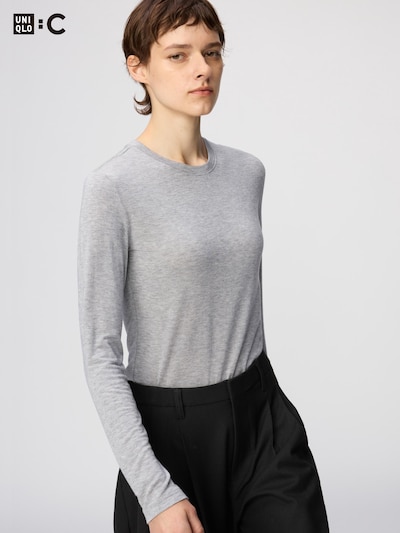 Model wearing a grey long-sleeve crew neck T-shirt tucked into black pants.