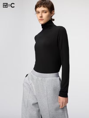 Model wearing a black long-sleeve turtleneck top against a plain background.