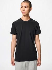 A model wearing a black crew-neck cotton T-shirt against a plain light background.