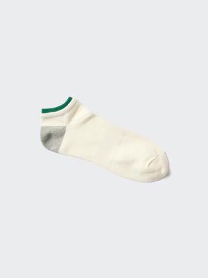 A cream-colored heattech half sock with a gray heel and a green cuff stripe laid flat on a light background.