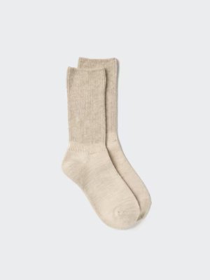 A pair of beige ribbed socks laid flat on a light background.