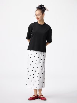 Model wearing the white narrow skirt with black polka dots, paired with a black top.