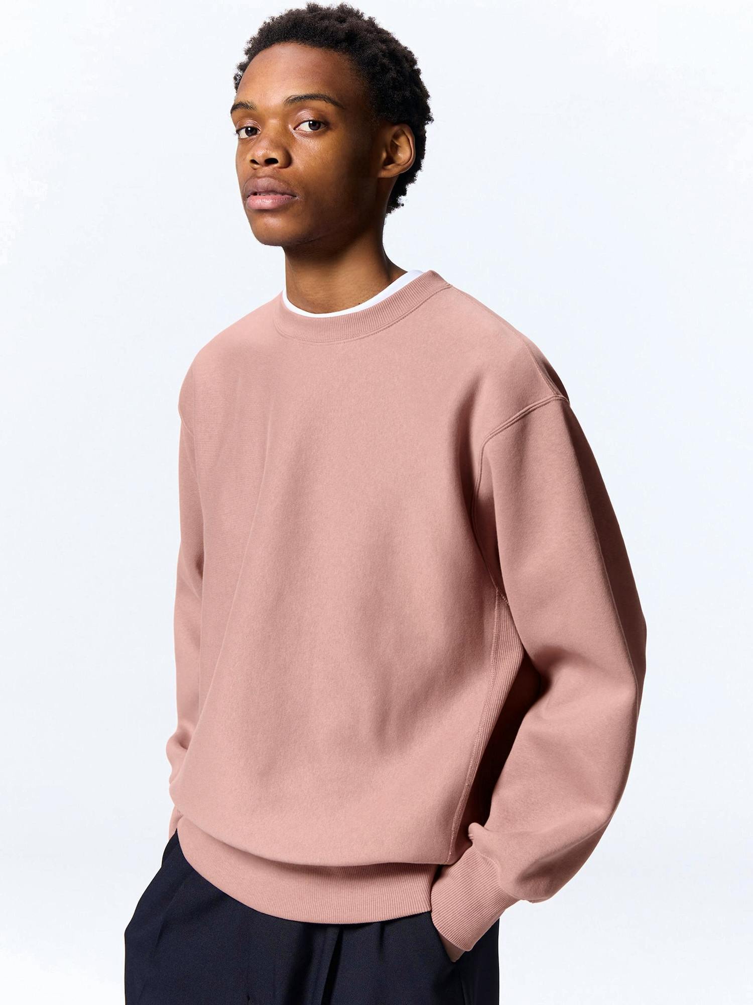 A model wearing a pink heavyweight long-sleeve sweatshirt pullover shown from mid-torso up.