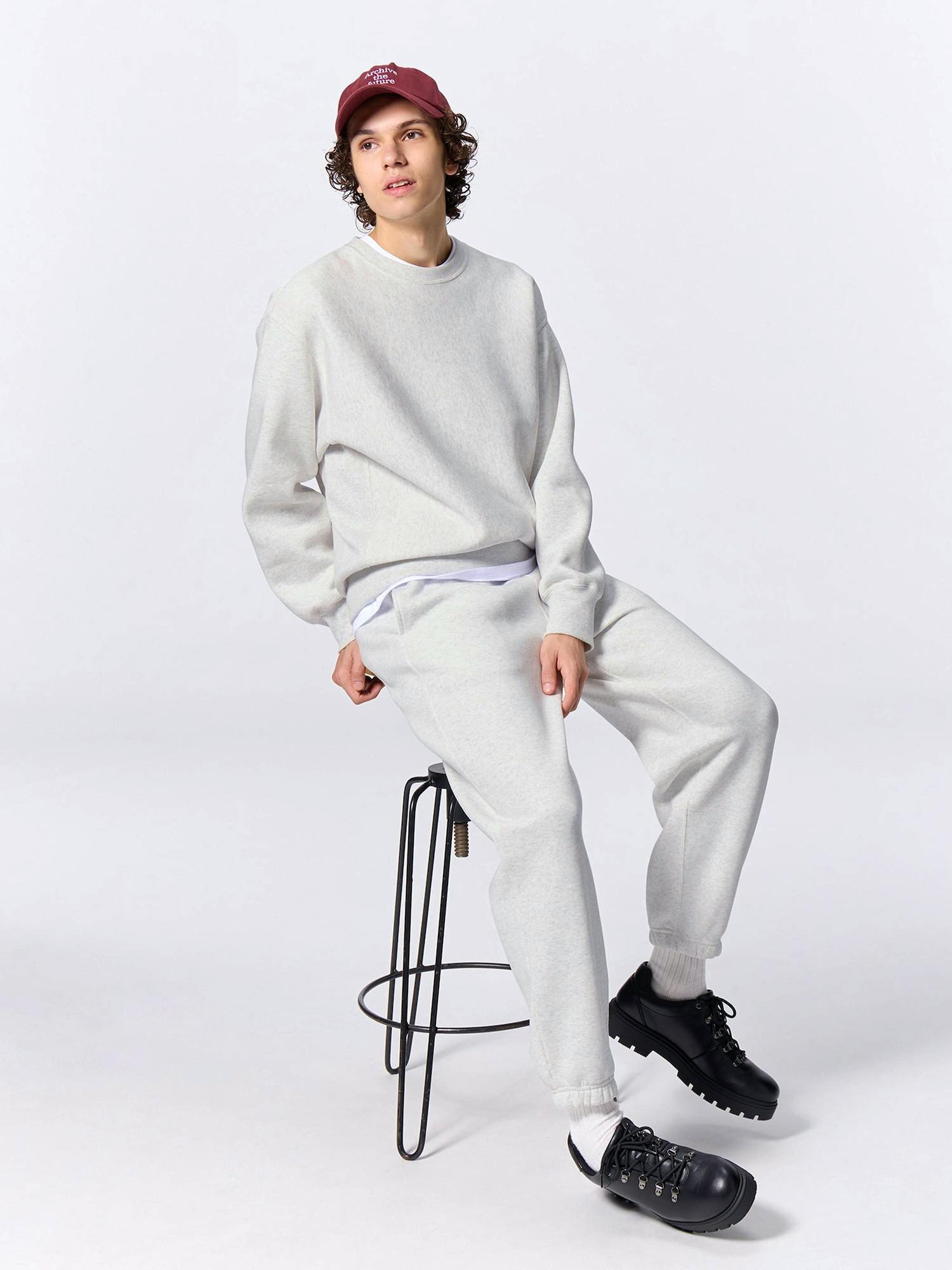 Seated model wearing the heavyweight sweat wide easy pants shown as part of a matching set.