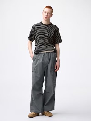 A model wearing wide straight sweatpants standing against a white background.