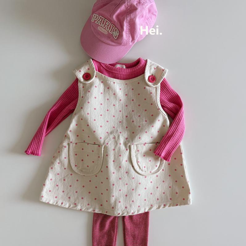 Cream polka-dot cotton women's dress with front pockets displayed flat over a pink long-sleeve top and pink cap.
