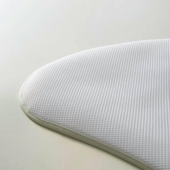 Close-up of a white height-adjustment pad / pillow cover with a textured mesh surface and rounded edge.