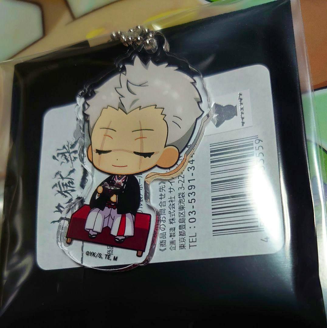 Photo of the trading acrylic decorative stand (アクスタ) in its packaging showing the chibi character seated on a red bench with a barcode label visible behind it.