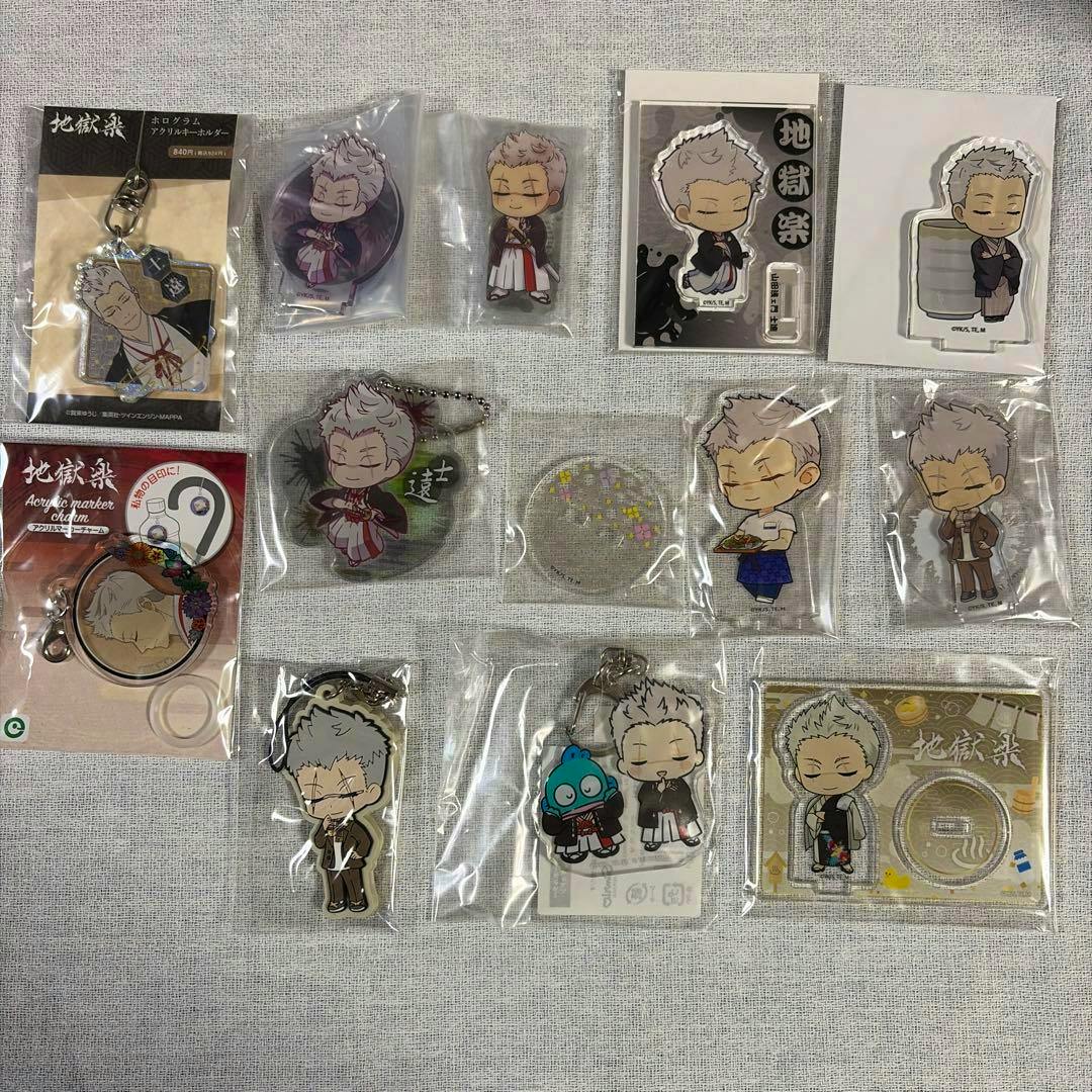 Multiple sealed acrylic keychains and stands featuring the Yamada Asaemon character arranged on a fabric background.