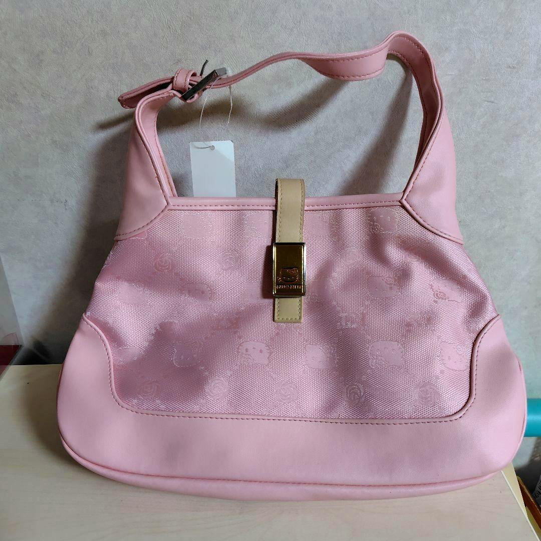 Pink Hello Kitty handbag with monogram pattern, gold clasp, and a paper tag attached.