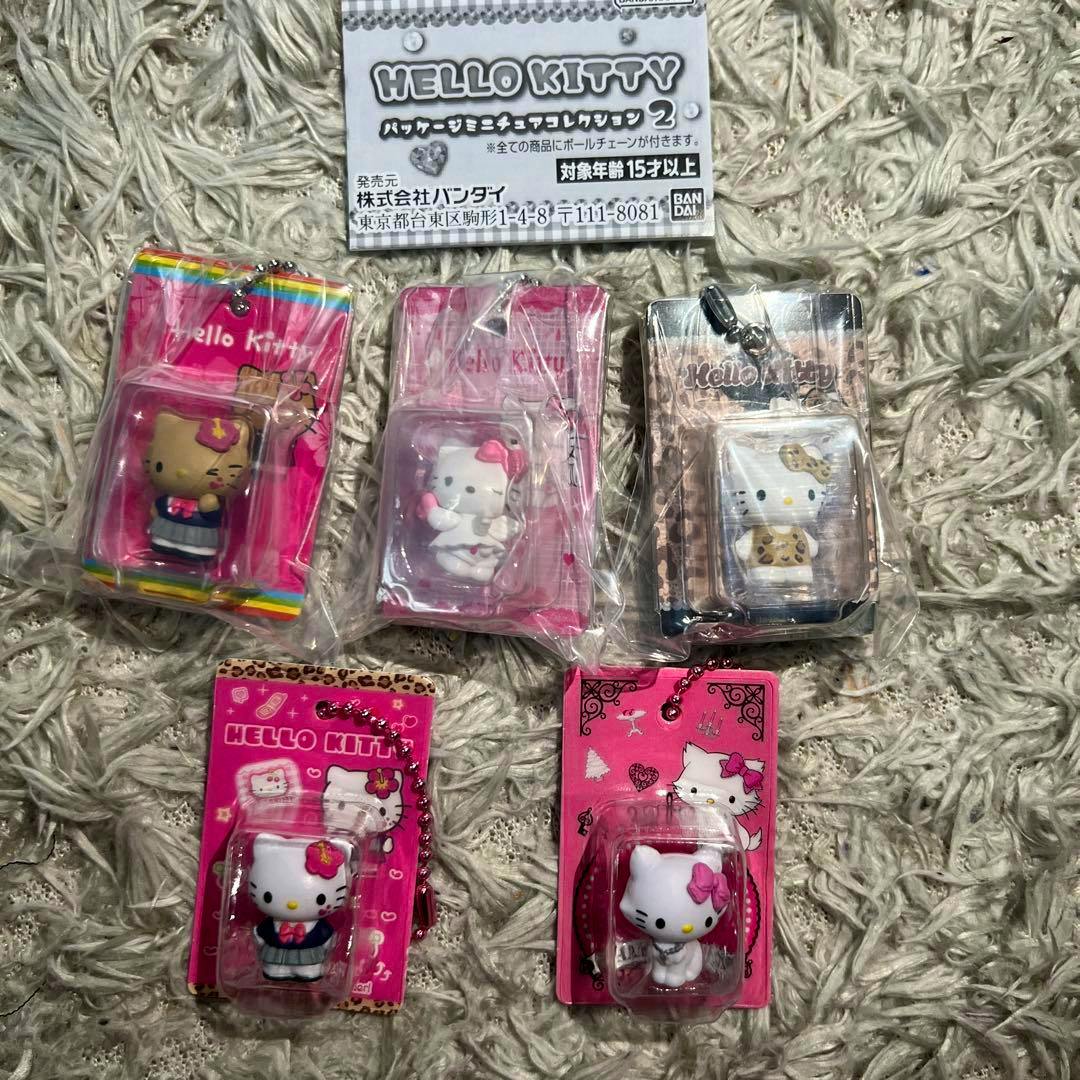 Five Hello Kitty packaged mini plastic figure keychains from the miniatures collection displayed on a shag rug.
