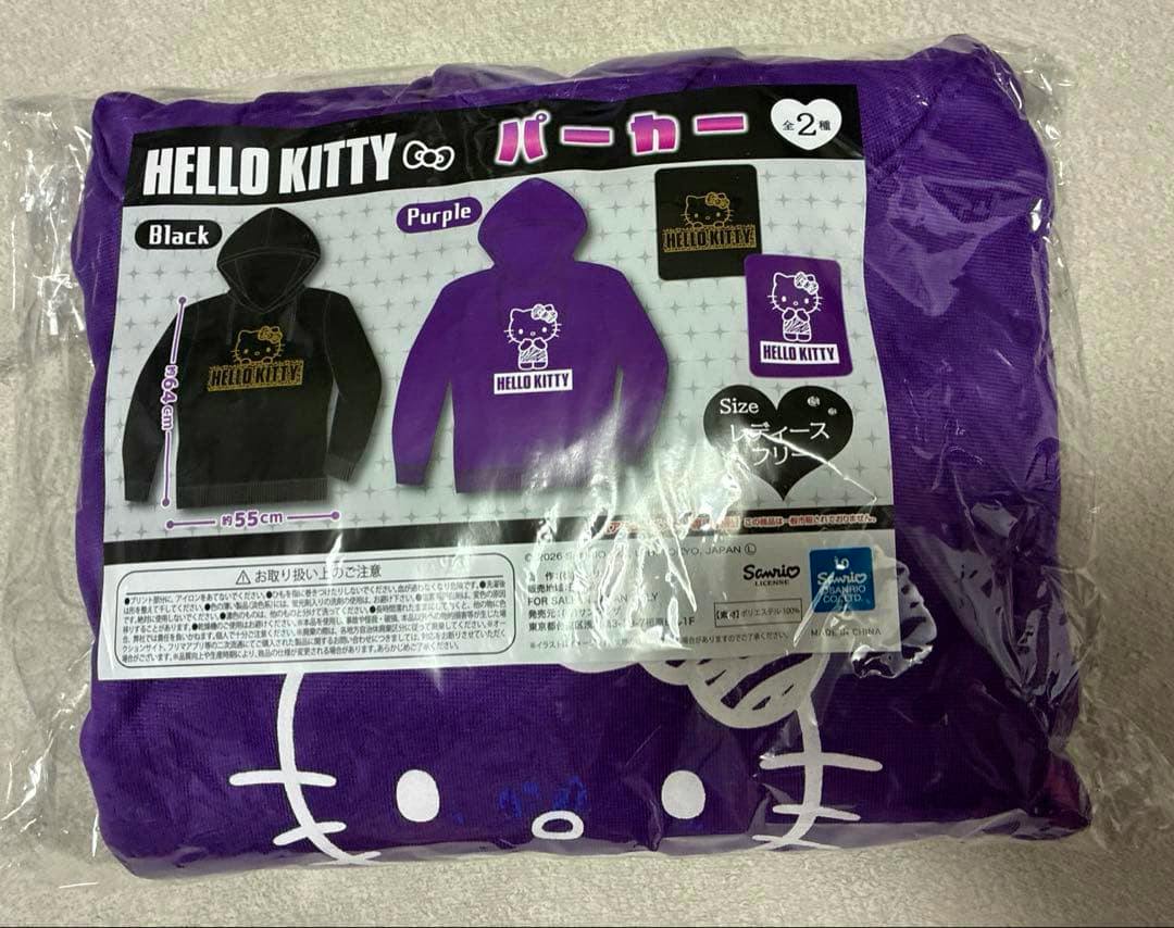 Folded purple Hello Kitty hoodie in clear plastic packaging with a label showing illustrations of the hoodie and product details.