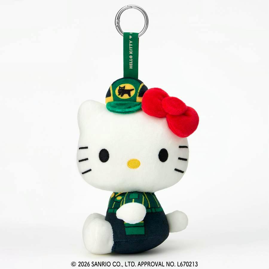 White Hello Kitty plush keychain wearing a green Yamato-style uniform and hat with a red bow, hanging from a green strap and metal keyring against a white background.