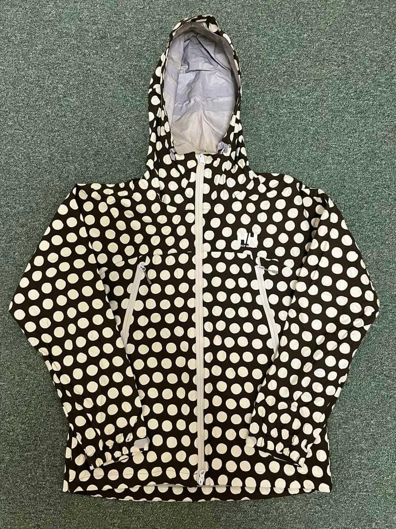 Front view of a HELLY HANSEN polka-dot mountain parka laid flat showing the hood, full-length front zipper, and zippered hand pockets.
