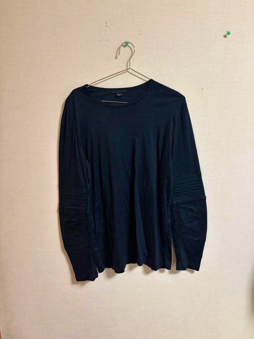 Black long-sleeve T-shirt (1999aw Helmut Lang astro biker) hanging on a hanger against a beige wall.