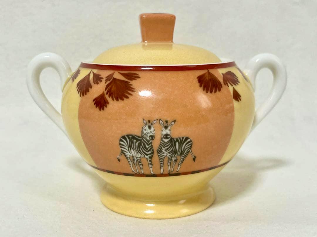 Front view of a HERMES sugar pot with lid showing two zebras, yellow-orange background, leaf motifs, and two handles.