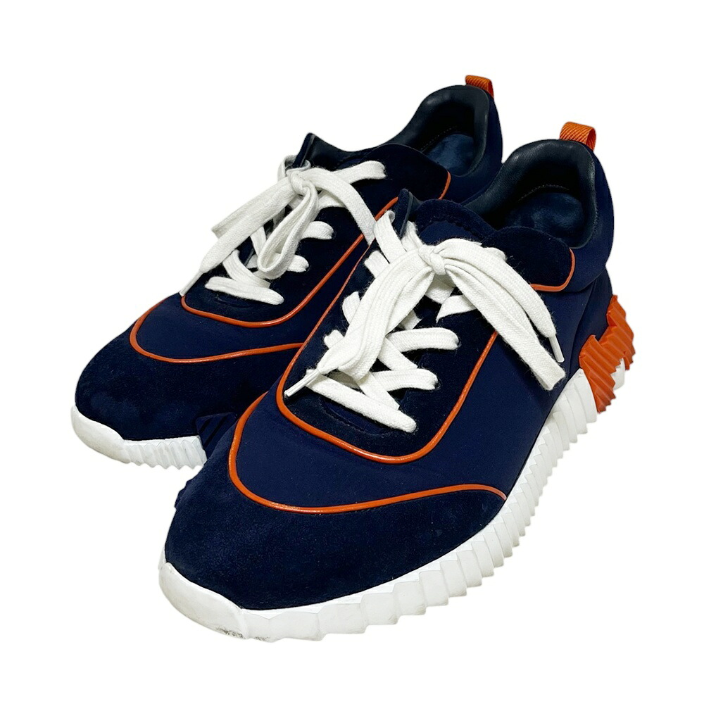 Pair of HERMES “Bouncing” navy and orange men's sneakers (size 42) shown on a white background.