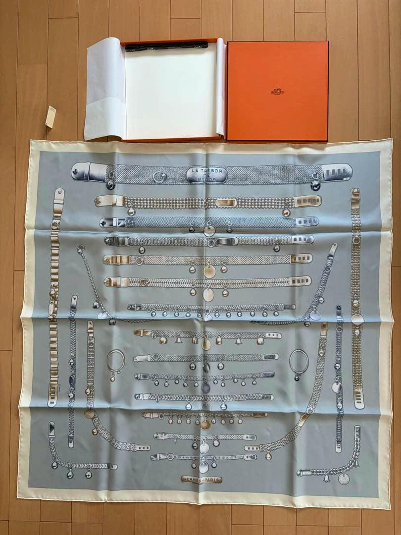 Hermès silk carré 90 "Le Trésor de Médor" scarf laid flat showing the full print, with the orange Hermès box visible at the top.
