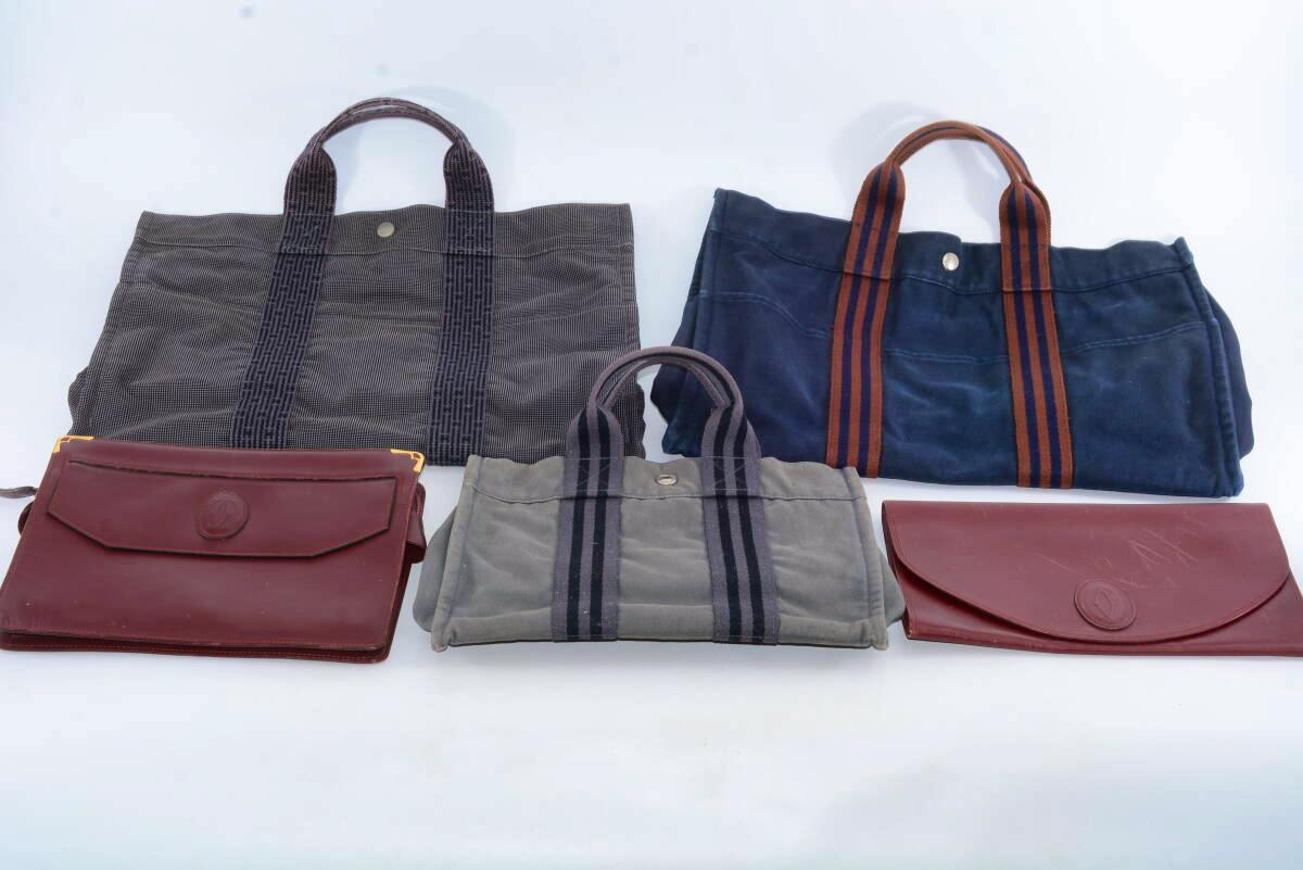 Five bags (canvas totes and leather clutches) arranged on a white background showing the full set.