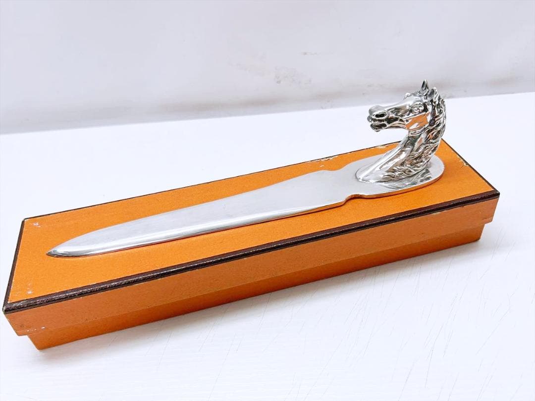 Silver horse-head paper knife resting on an orange box.