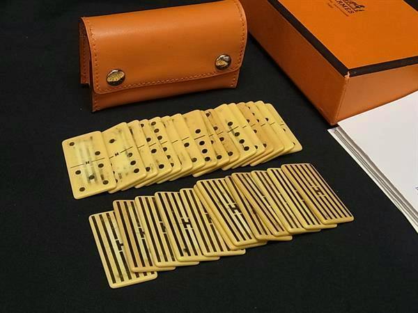Mini domino tiles arranged in two rows with an orange leather case and orange box on a black surface.