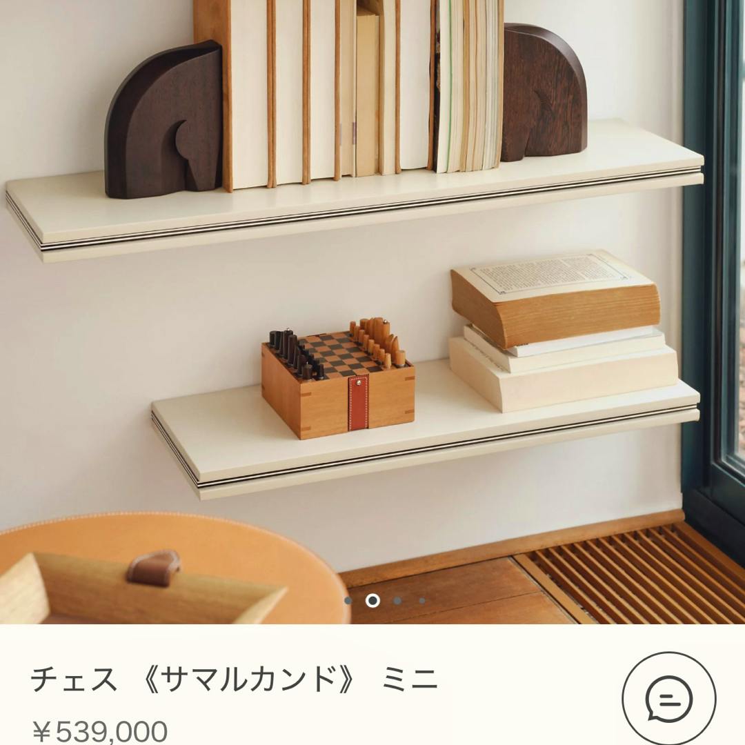 Small wooden Hermès Samarkand mini chess set displayed on a shelf next to stacked books.