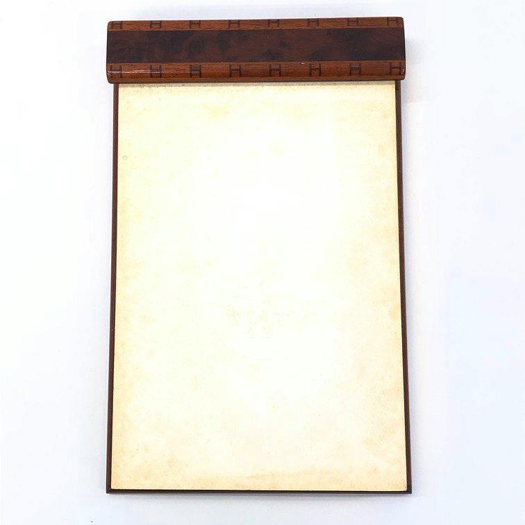 Top-down view of the HERMES wooden memo pad stand showing the wood-grain top bar and a blank notepad held beneath.