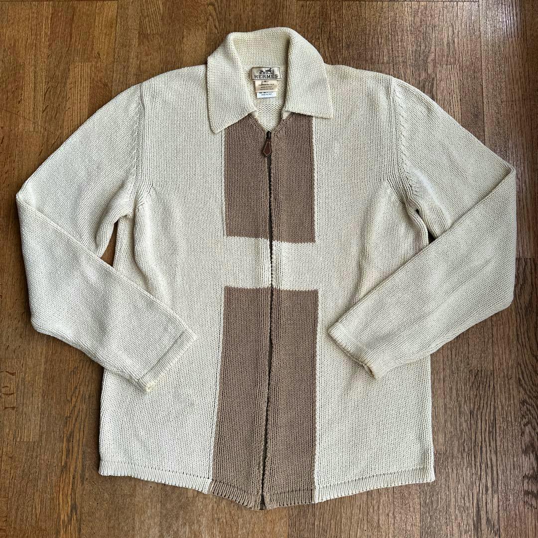 Beige HERMES zip-up knit sweater laid flat showing the front with collar, long sleeves, and brown vertical knit panels.