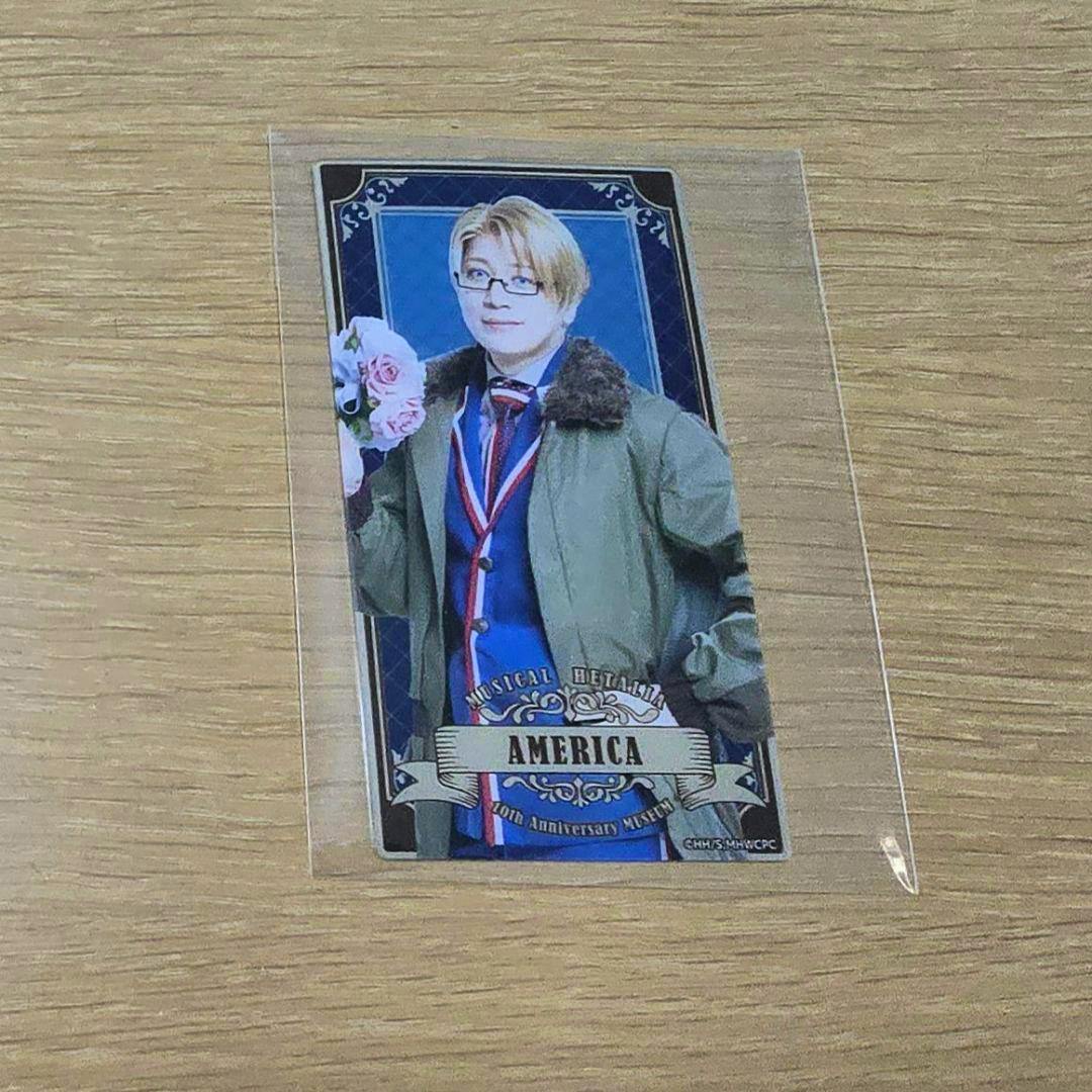 A photo of an acrylic card in a clear sleeve showing a character labeled "AMERICA" on a wooden surface.