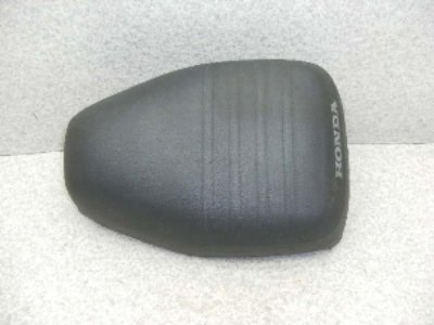 Top view of a black motorbike seat with horizontal ribbing on a neutral background.