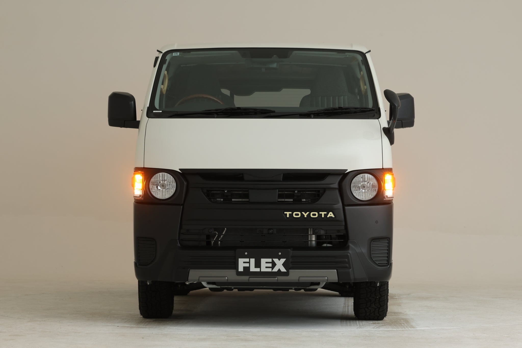 Front view of a white Hiace van showing the front light panel with the left turn signal illuminated.