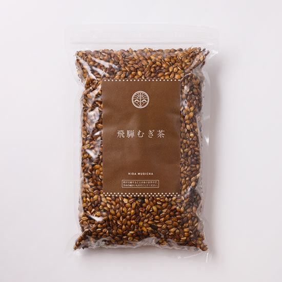 A clear plastic bag of mugicha (roasted barley tea) grains with a brown label showing the product name.