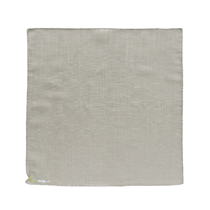 A square gray handkerchief laid flat with a small embroidered chameleon in the lower-left corner.