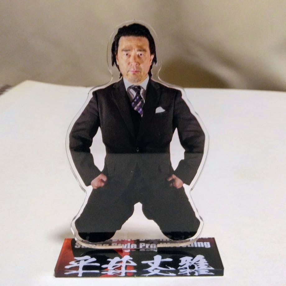 An acrylic decorative stand featuring a printed photo of a man in a suit mounted on a rectangular base with Japanese text.