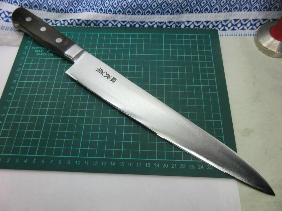 29 cm chef knife (gyuto) with a full-steel blade and dark handle lying on a green cutting mat.