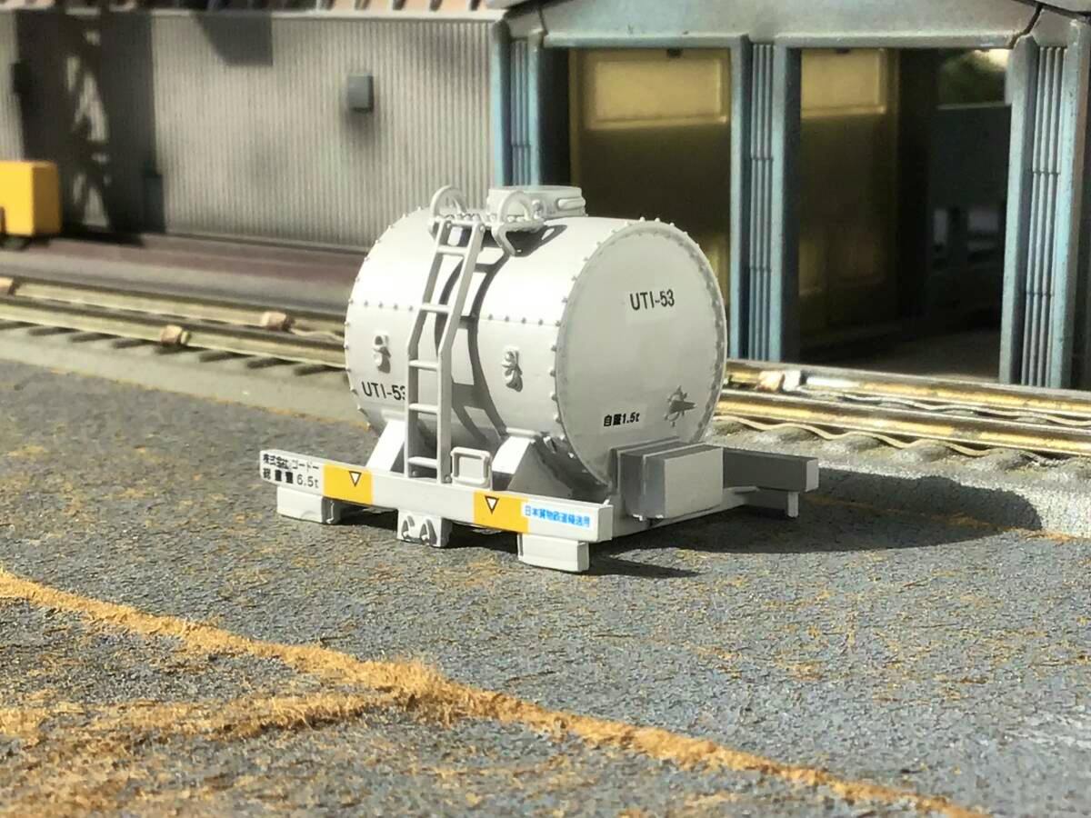 HO-scale UT1-53 tank container model shown on a model railway surface in front of a building.