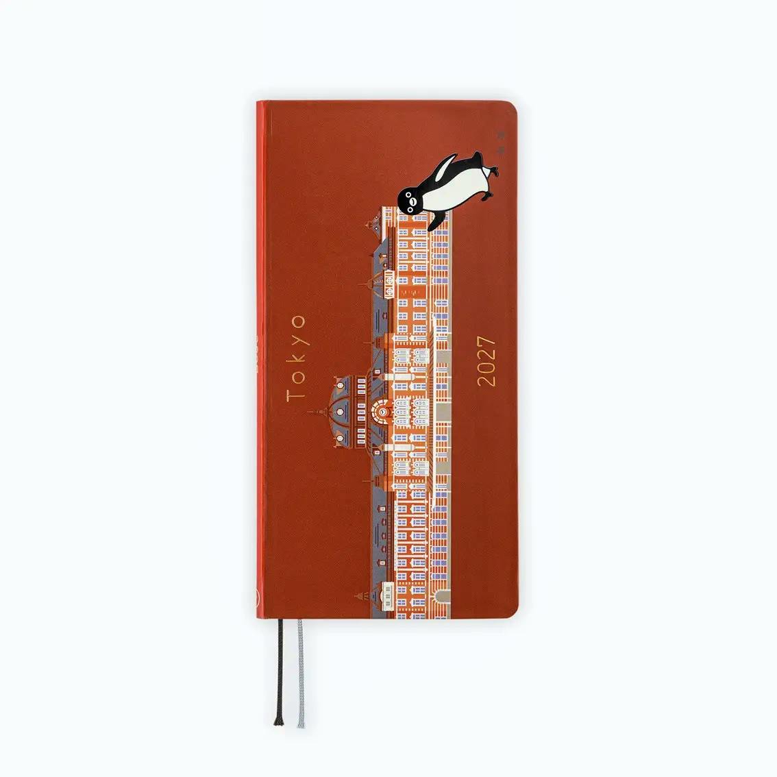 Closed ほぼ日手帳2027 weeks diary showing the brown-red Tokyo building cover design with the Suica penguin and two ribbon bookmarks.