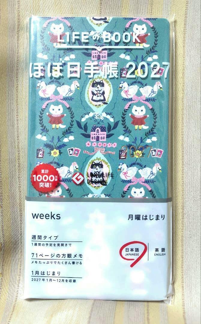 Front view of the wrapped ほぼ日手帳 2027 weeks diary showing the patterned cover and white "weeks" belly band.